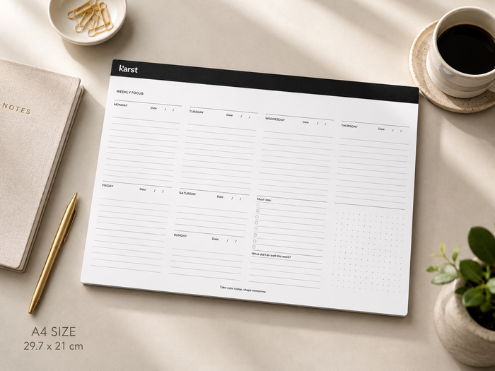 Karst A4 weekly desk planner on a neutral desk with gold pen, coffee, notebook, and soft natural light.